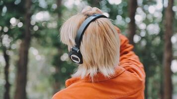 attraktiv jung bärtig Mann chatten auf Sozial Medien während spazieren. tragen Weiß Kopfhörer und Hören zu Musik- haben positiv Emotionen im sonnig Herbst Tag. entspannen Zeit. gehen. video