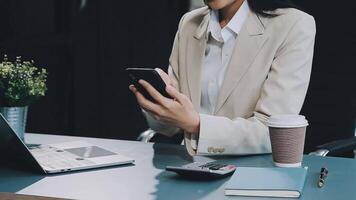 femme d'affaires asiatique en costume formel au bureau heureuse et joyeuse lors de l'utilisation d'un smartphone et du travail video