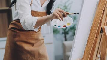 Over the shoulder selective focus shot of male artist using brush while adding color paint to pencil drawing on canvas video