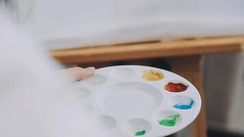 al di sopra di il spalla selettivo messa a fuoco tiro di maschio artista utilizzando spazzola mentre aggiungendo colore dipingere per matita disegno su tela video