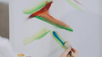 sobre a ombro seletivo foco tiro do masculino artista usando escova enquanto adicionando cor pintura para lápis desenhando em tela de pintura video