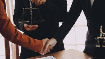 Lawyer shaking hands with a client making about documents, contracts, agreements, cooperation agreements with a female client at the lawyer's desk and a hammer at the table. video