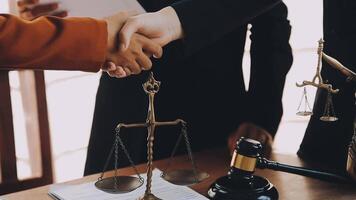 Lawyer shaking hands with a client making about documents, contracts, agreements, cooperation agreements with a female client at the lawyer's desk and a hammer at the table. video