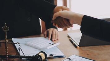 Lawyer shaking hands with a client making about documents, contracts, agreements, cooperation agreements with a female client at the lawyer's desk and a hammer at the table. video