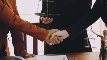 Lawyer shaking hands with a client making about documents, contracts, agreements, cooperation agreements with a female client at the lawyer's desk and a hammer at the table. video