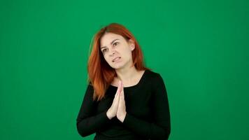 The red-haired girl pats her shoulder and then folds her hands as if praying. Green background video