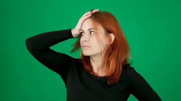 of girl with thoughtful facial expression excitement, hand on head woman on a green background in a chroma key studio emotions close-up brown eyes Light skin European American. Canadian. video