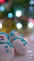 Snowman dessert macaron decorated with hat and scarf with colorful lights and bokeh flashing on foreground and Christmas tree on background. Merry Christmas and Happy New Year festive concept video