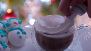 aggiungendo crema nel cacao bicchiere bicchiere vicino il Natale albero per Natale meringa pupazzo di neve delizioso cibo divertimento cucinando nuovo anno celebrazione video