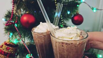 New Year Christmas clatter glasses of hot chocolate cocoa with cream and straws Christmas tree bright red toys lights family gatherings celebration drinking hot drink in evening near tree video