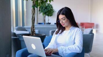 Smiling girl freelancer chatting with client while resting at cafe, using laptop video