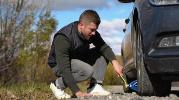 A young man with a gray car that broke down on the road. Changing tire on broken car on road video