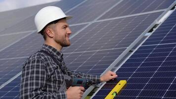 masculino engenheiro dentro protetora capacete instalando solar fotovoltaico painel sistema usando Chave de fenda. alternativo energia ecológico conceito video