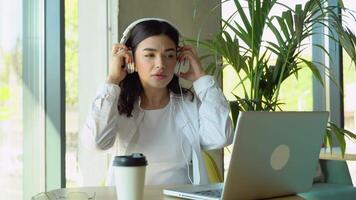 femme écoute la musique dans écouteurs tandis que séance dans café. relaxant temps avec la musique video