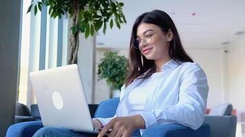Smiling girl freelancer chatting with client while resting at cafe, using laptop video