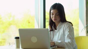 Smiling girl freelancer chatting with client while resting at cafe, using laptop video