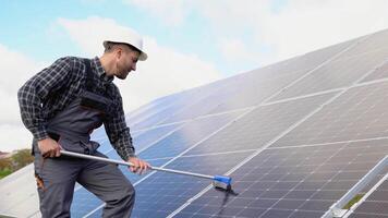 Male engineer cleaning solar panels with brush and water video