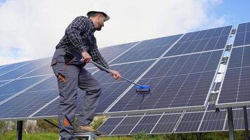 Male engineer cleaning solar panels with brush and water video