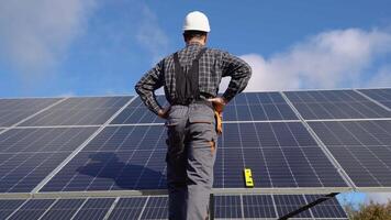 Man standing near solar panels. Back view. Solar power plant. Renewable energy video