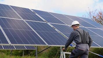 Funny worker in uniform cleaning solar panels with brush and water video