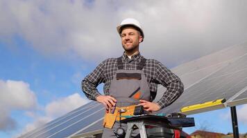 Portrait of confident engineer of solar cell farm industry. Close up portrait of male worker in protective helmet standing near solar panel video