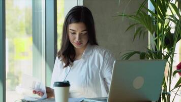 jung charmant weiblich Freiberufler mit Laptop Computer zum Entfernung Job während Sitzung im modern Kaffee Geschäft Innere. schön kaukasisch Frau Arbeiten auf Netbook während Morgen Frühstück im Cafe Bar video