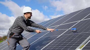 Worker in uniform cleaning solar panels with brush and water video