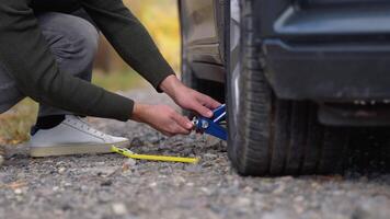 A young man with a gray car that broke down on the road. Changing tire on broken car on road video