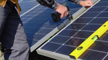manlig ingenjör i skyddande hjälm montera sol- solceller panel systemet använder sig av skruvmejsel. alternativ energi ekologisk begrepp video