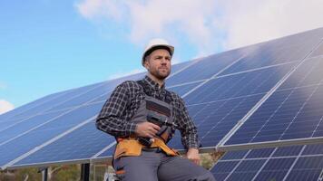 Portrait of confident engineer of solar cell farm industry. Close up portrait of male worker in protective helmet standing near solar panel video