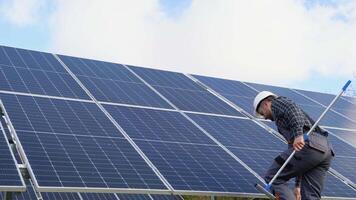 Male engineer cleaning solar panels with brush and water video