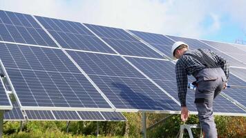 Male engineer cleaning solar panels with brush and water video