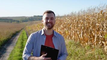 Caucasian farm worker walking along maize corn field for inspection. Harvest care concept video