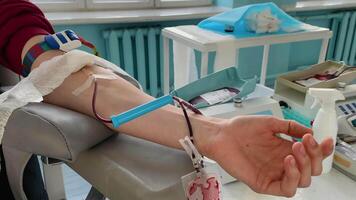 Young man making blood donation in hospital, focus on hand video
