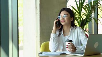 Female manager having conversation on cellphone while working online in cafe, having problem with financial reports. Remote work concept video