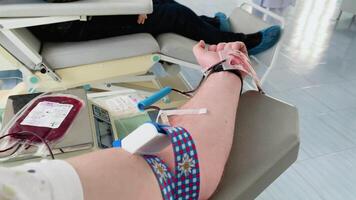 Young man making blood donation in hospital, focus on hand video