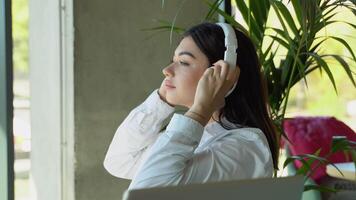 mulher ouvindo música dentro fones de ouvido enquanto sentado dentro cafeteria. relaxante Tempo com música video