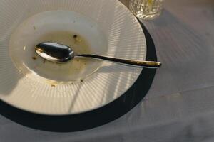 vacío plato con cuchara en el mesa después almuerzo. foto