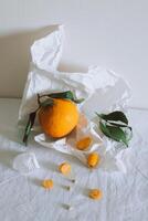 Fresh juicy citrus fruits with green leaves on white craft paper. Healthy food. photo