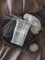 Hand knitted socks with needles and yarn ball in a basket. photo