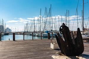 Old anchor on embankment near Marina. Bright blue sky and skyscapers on background. Tel Aviv city, Israel. photo