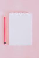 Notebook with blank page and pencil on pink background. photo