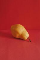 Ripe yellow pear on a bright red background. photo