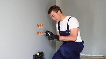 Close up of man installing electrical outlet in wall in room of house. Man doing electrics video