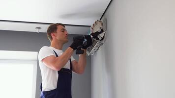 Worker in uniform installs air conditioner in the apartment. Construction, maintenance and repair concept video