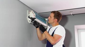 Worker in uniform installs air conditioner in the apartment. Construction, maintenance and repair concept video