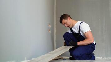 lavoratore installazione di legno laminato pavimento. lavoratore posa parquet pavimentazione video