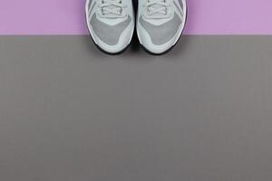 Grey sneakers on the violet and grey background. Concept for healthy lifestyle and everyday training. photo