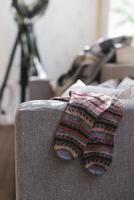 Hand knitted socks on the sofa in modern interior. Natural colors. photo