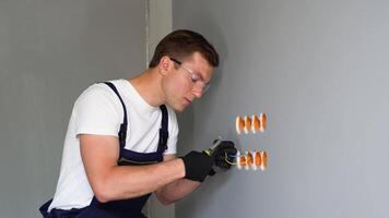 Professional electrician technician installing a wall socket in a new house. Electrician mounting wiring for electric sockets video